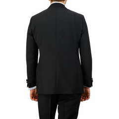 Back view of a person wearing a Black Wool Mohair Tuxedo Jacket by Baltzar Sartorial and matching pants.