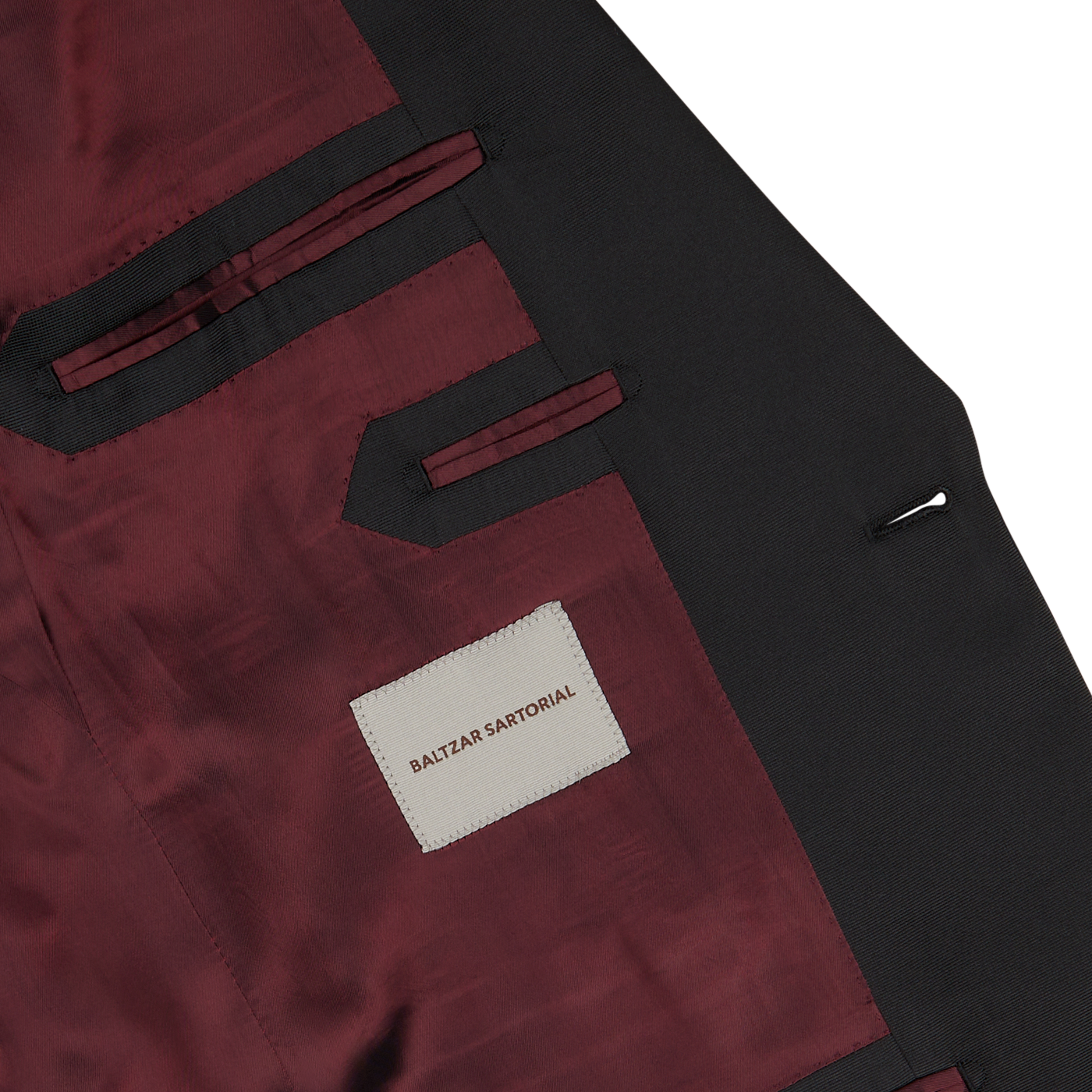 The inside lining of the Black Wool Mohair Tuxedo Jacket features a deep red color with black accents, multiple pockets, and a label that reads "Baltzar Sartorial.