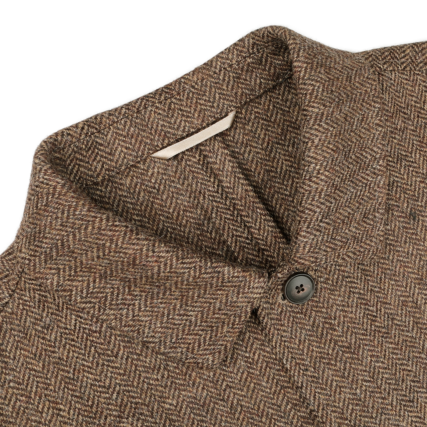 Close-up of a Brown Herringbone Wool Tweed Utility Jacket by Baltzar Sartorial, showcasing a single black button on the collar and a white label inside.