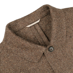 Close-up of a Brown Herringbone Wool Tweed Utility Jacket by Baltzar Sartorial, showcasing a single black button on the collar and a white label inside.