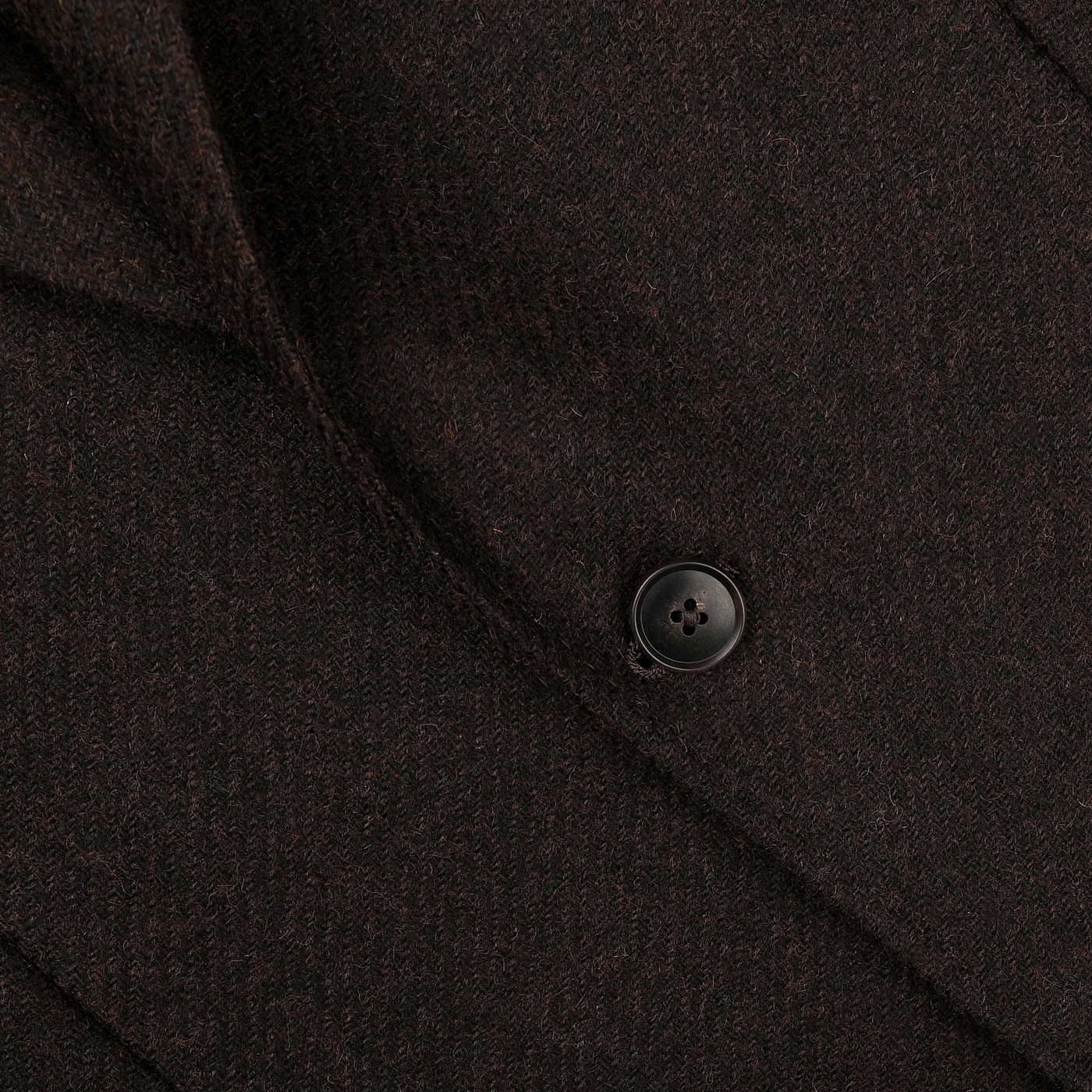 A close-up of the Baltzar Sartorial Dark Brown Wool Tweed Blazer showcases a single black button and the intricate texture of its Abraham Moon fabric.