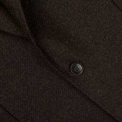 A close-up of the Baltzar Sartorial Dark Brown Wool Tweed Blazer showcases a single black button and the intricate texture of its Abraham Moon fabric.