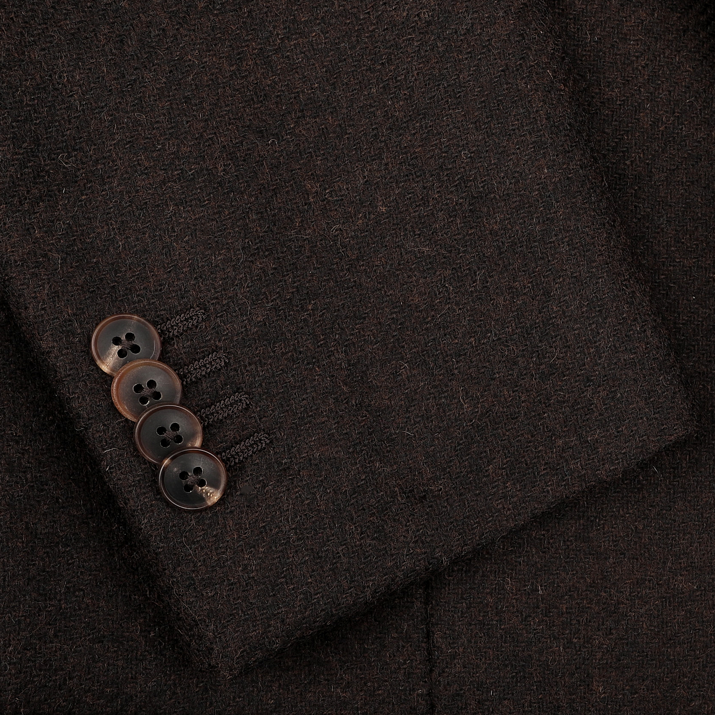 Close-up of the cuff of the Dark Brown Wool Tweed Blazer by Baltzar Sartorial, showcasing four black buttons on the sleeve, crafted in pure wool tweed.