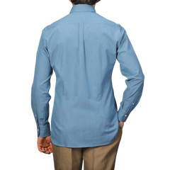 A person is facing away from the camera, wearing the Denim Blue Cotton Twill BD Western Shirt by Baltzar Sartorial with beige pants. Its regular fit and pure cotton twill enhance its classic appeal.