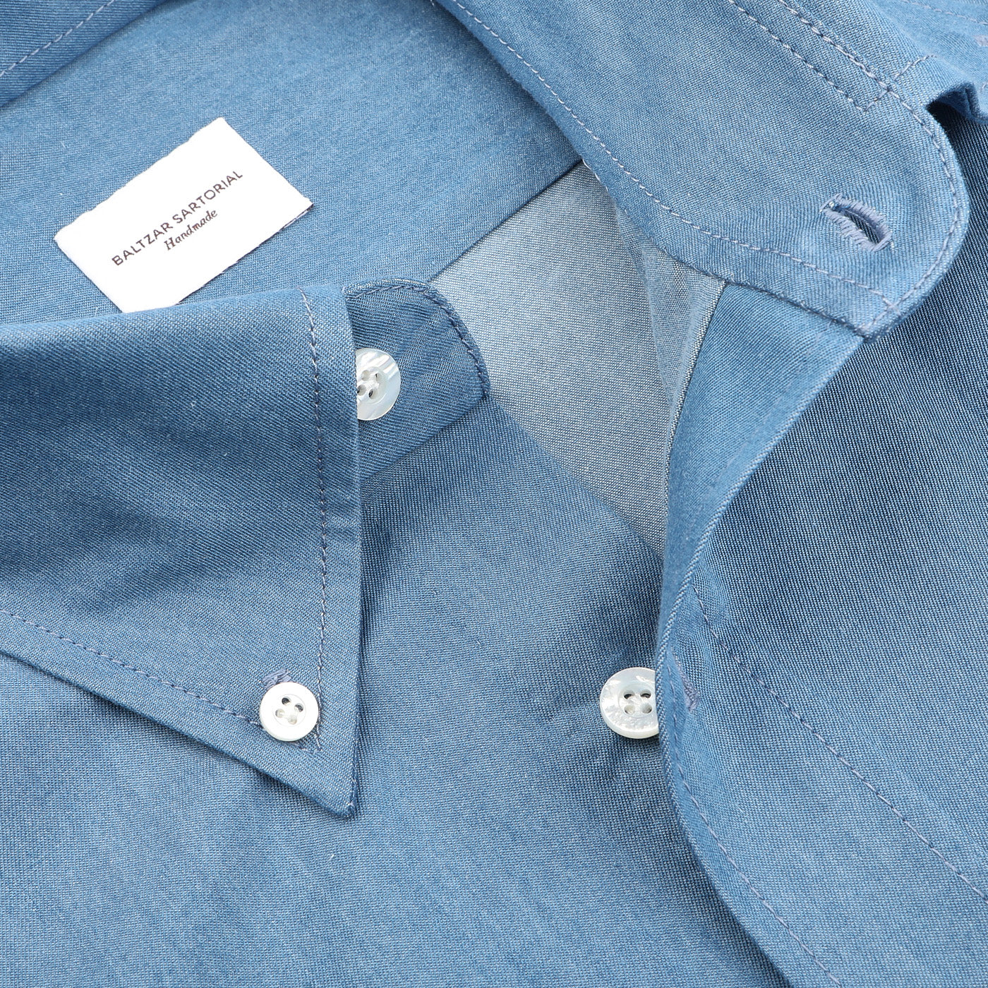 Close-up of the Denim Blue Cotton Twill BD Western Shirt by Baltzar Sartorial, showcasing a regular fit with a button-down collar and visible label, crafted for comfort and style.