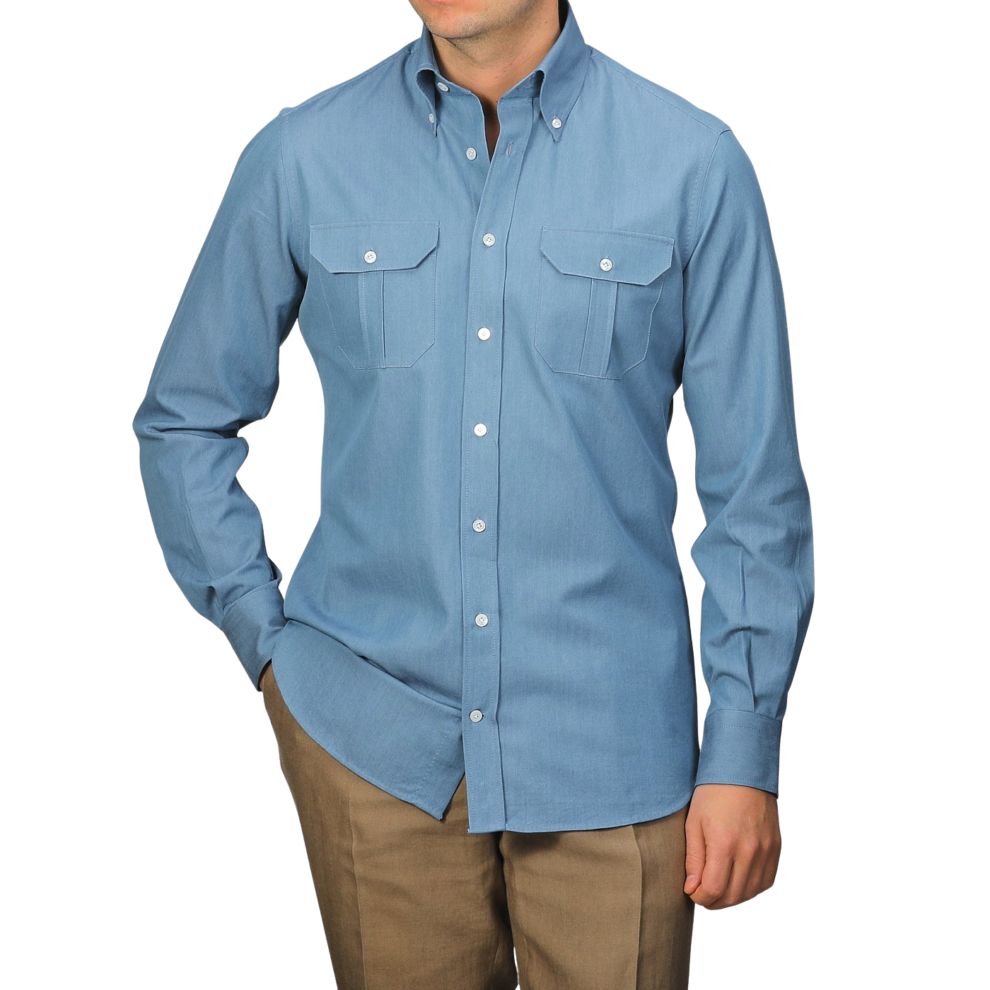 A man stands against a gray background, wearing a Denim Blue Cotton Twill BD Western Shirt by Baltzar Sartorial, paired with brown pants.