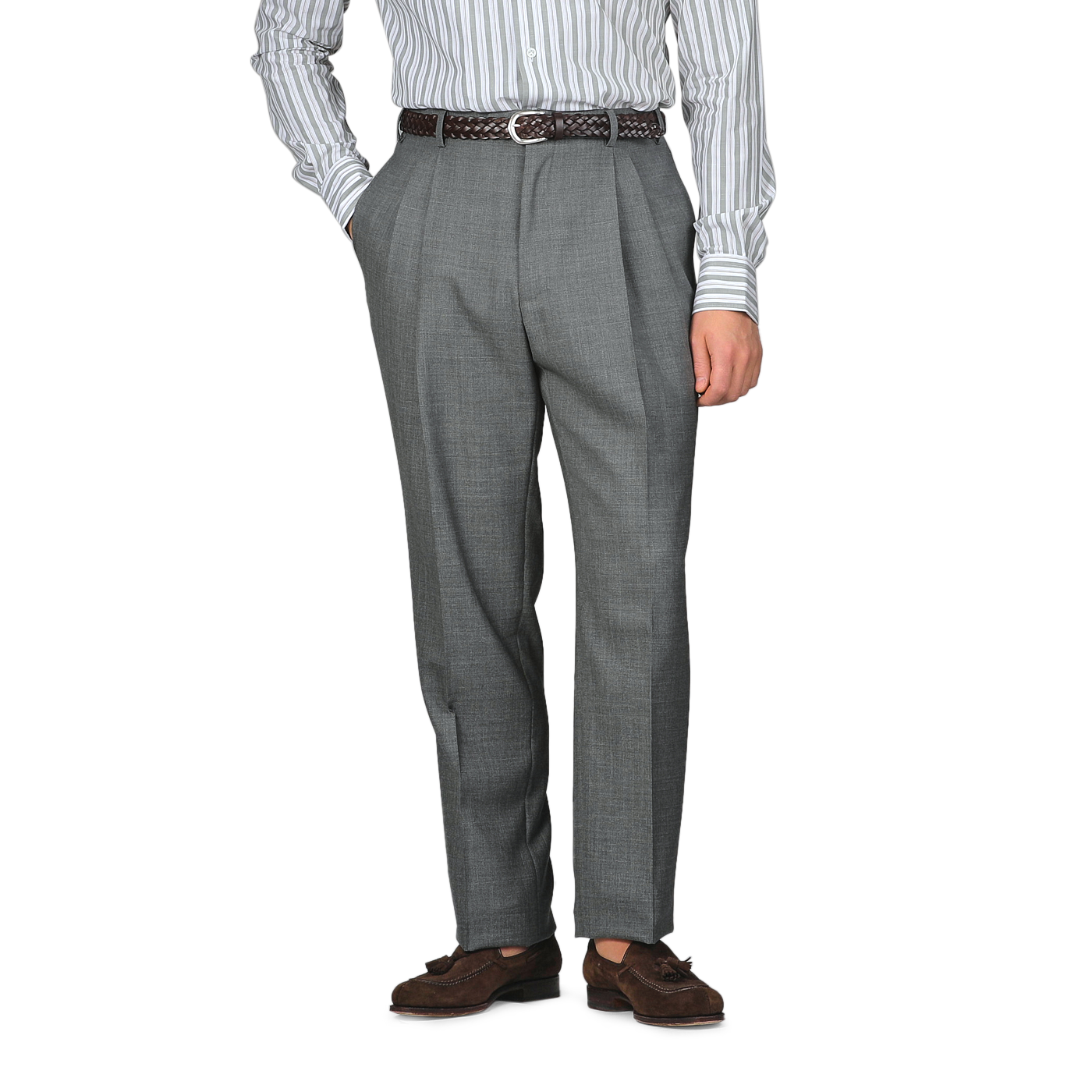 A person is dressed in Baltzar Sartorial Grey High-Twist Wool Pleated Trousers and a striped shirt, hands in pockets, complemented by a brown belt and shoes.