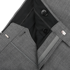 Close-up of Baltzar Sartorial Grey High-Twist Wool Pleated Trousers highlighting the tailored fit's waistband, black lining, buttons, and zipper.