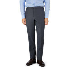 Man in a blue shirt and Baltzar Sartorial Grey Super 100's Wool Flat Front Suit Trousers standing against a white background, focus on trousers.