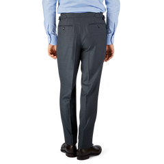 Man standing back-to-camera wearing a blue shirt and Baltzar Sartorial Grey Super 100's Wool Pleated Suit Trousers with black shoes on a plain background.