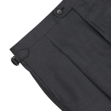 Close-up of Baltzar Sartorial Grey Super 100's Wool Pleated Suit Trousers with a side adjuster and button closure.