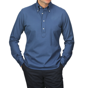 Someone wearing the Indigo Blue Cotton Piqué BD Popover Shirt from Baltzar Sartorial and dark pants, standing against a light gray background.