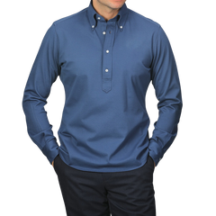 Someone wearing the Indigo Blue Cotton Piqué BD Popover Shirt from Baltzar Sartorial and dark pants, standing against a light gray background.