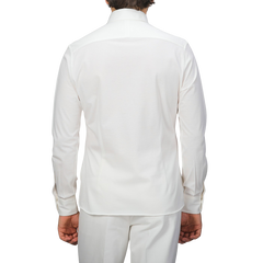 Rear view of a person wearing a Baltzar Sartorial Ivory White Cotton Piqué BD Popover Shirt and matching white pants against a plain background.