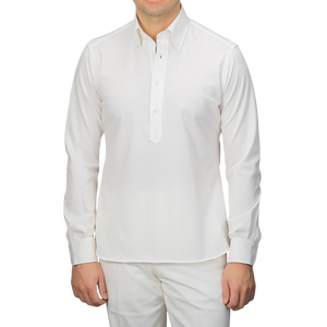 A person in an Ivory White Cotton Piqué BD Popover Shirt by Baltzar Sartorial and white pants, facing forward.