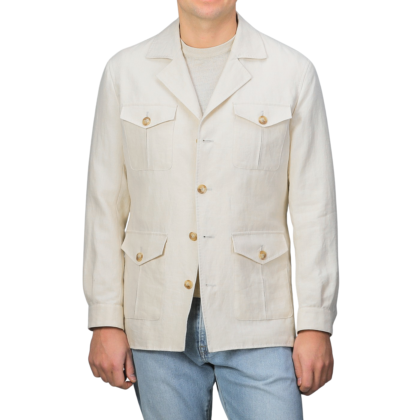 A man in a Light Beige Pure Linen Safari Jacket by Baltzar Sartorial, featuring multiple pockets and mid-weight linen, stands beside light blue jeans against a plain backdrop.