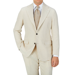 A man is posing in a Light Beige Pure Linen Suit Jacket by Baltzar Sartorial, consisting of a suit jacket and tailored trousers.