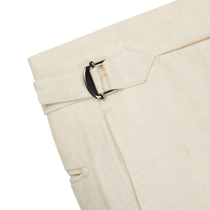 A close up of Baltzar Sartorial Light Beige Pure Linen Flat Front Trousers with a buckle.