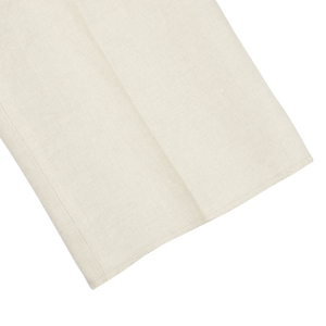 A light beige pure linen napkin on a flat surface. (Brand Name: Baltzar Sartorial)