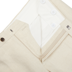 A close up of Light Beige Pure Linen Flat Front Trousers from Baltzar Sartorial with buttons and a tailored fit.