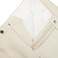 A close up of Light Beige Pure Linen Flat Front Trousers from Baltzar Sartorial with buttons and a tailored fit.