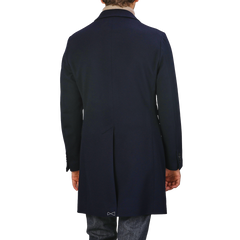 A person wearing a Baltzar Sartorial Navy Blue Loro Piana Wool Tailored Coat and jeans is viewed from the back against a plain background.