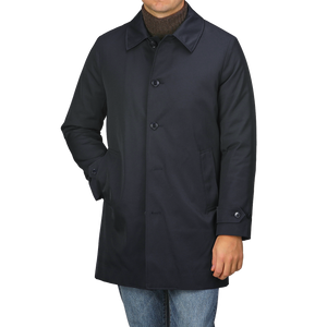 A person is standing against a plain background wearing the Navy Blue Nylon Thermore Padded Car Coat by Baltzar Sartorial, featuring button closure and Thermore Ecodown lining, paired with jeans.