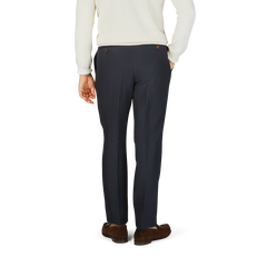 The back view of a man wearing Baltzar Sartorial navy blue pure linen pleated trousers and a white sweater.