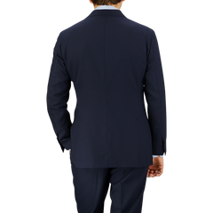 A man viewed from behind, wearing a well-fitted Navy Blue Super 100s Wool DB Suit Jacket by Baltzar Sartorial, standing against a striped, translucent background.