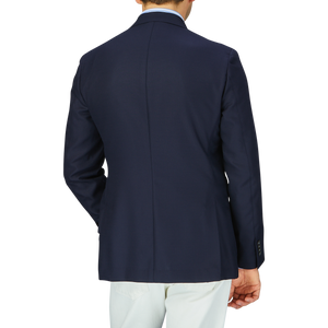 A man wearing a Baltzar Sartorial navy blue wool hopsack blazer and white trousers viewed from the back.