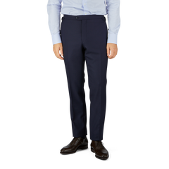 A cropped image of a man dressed in a light blue shirt and Baltzar Sartorial Navy Super 100's Wool Flat Front Suit Trousers with black dress shoes, standing against a white background.