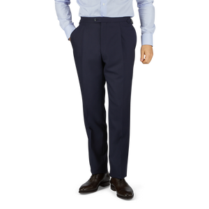 Man in a light blue shirt and Baltzar Sartorial Navy Super 100's Wool Pleated Suit Trousers standing against a white background, showing only from the waist down.