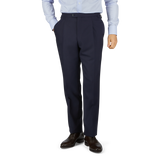 Man in a light blue shirt and Baltzar Sartorial Navy Super 100's Wool Pleated Suit Trousers standing against a white background, showing only from the waist down.
