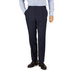 Man in a light blue shirt and Baltzar Sartorial Navy Super 100's Wool Pleated Suit Trousers standing against a white background, showing only from the waist down.