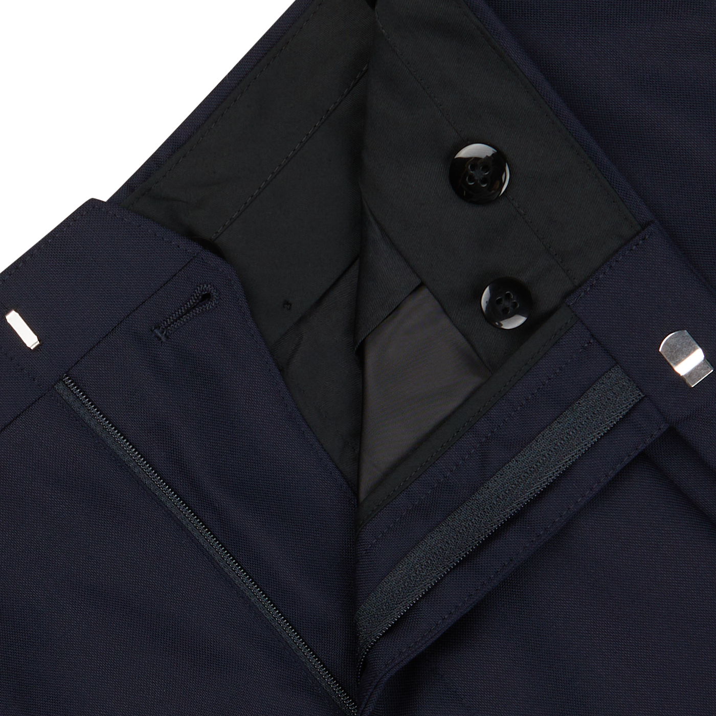 Close-up of a Navy Super 100's Wool Pleated Suit Trousers from Baltzar Sartorial with black buttons, a zipper, and visible inner lining.