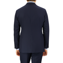 Rear view of a man wearing a Baltzar Sartorial Navy Super 100's Wool Suit Jacket and matching pants, against a grey background.