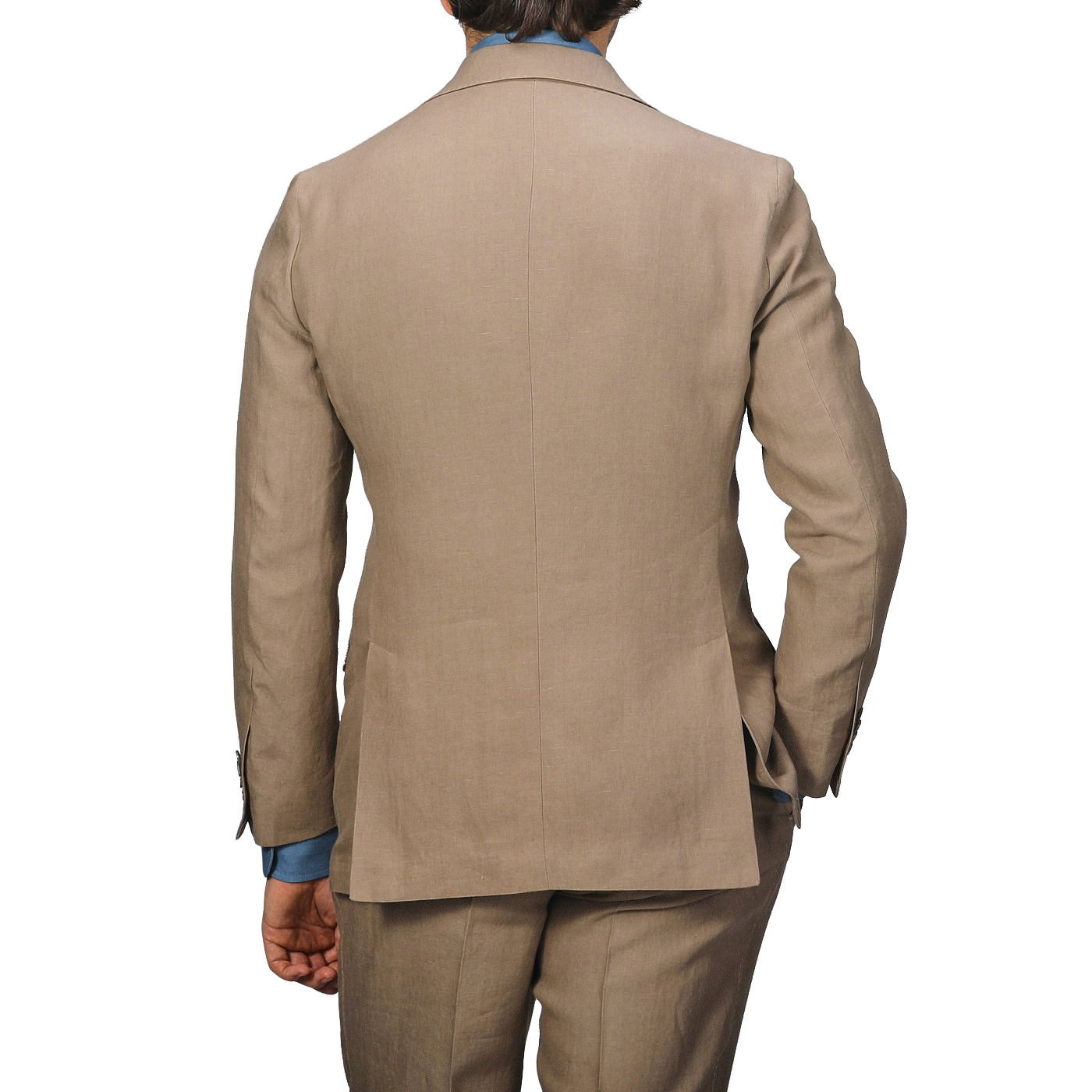 Back view of a person wearing a taupe beige pure linen suit jacket and blue shirt, hands in pockets, against a plain background. This Baltzar Sartorial outfit is completed with impeccably tailored trousers.