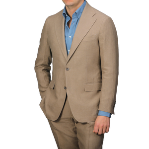 A person in a Taupe Beige Pure Linen Suit Jacket by Baltzar Sartorial and a blue dress shirt stands against a plain background, exuding refined elegance.