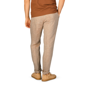 The back of a man wearing Berwich beige linen herringbone drawstring trousers and a tan t-shirt.
