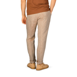The back of a man wearing Berwich beige linen herringbone drawstring trousers and a tan t-shirt.
