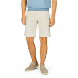 Man standing in Berwich cream beige cotton blend Bermuda shorts and light-colored sneakers.
