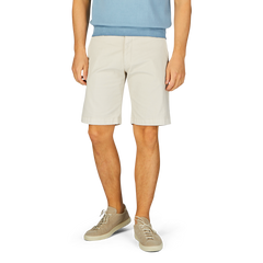 Man standing in Berwich cream beige cotton blend Bermuda shorts and light-colored sneakers.