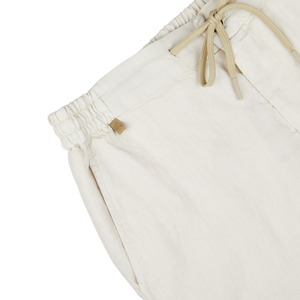Close-up of a Berwich cream beige washed linen drawstring shorts' waistband with a metal brand tag.