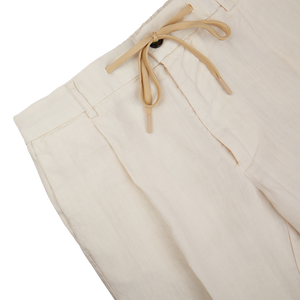 A pair of Cream Linen Twill Drawstring Trousers with tan drawstring ties by Berwich.