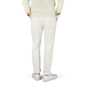 A man in Berwich cream white cotton stretch chinos and sweater.