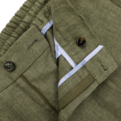 Close-up of Berwich's Green Linen Herringbone Drawstring Trousers featuring a slim fit, buttoned waistband, and partially open zipper that reveals a hint of blue inner lining.