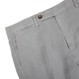 A pair of light grey Berwich linen-lyocell pants with buttons on the side.