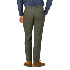 A person wearing Berwich Moss Green Herringbone Wool Tweed Trousers and brown suede shoes is shown from the back, with hands relaxed at their sides, against a plain background.