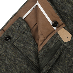 Close-up of Berwich's Moss Green Herringbone Wool Tweed Trousers, showcasing the waistband and inner lining adorned with a beige tag. The pure wool pants feature a classic herringbone pattern and are equipped with both button and zipper closures.