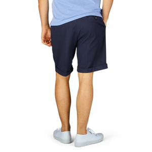 Man standing side-on showcasing Berwich navy blue cotton blend pleated shorts and white sneakers.